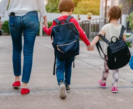 Une maman conduit ses quatre enfants à l'école en leur donnant la main