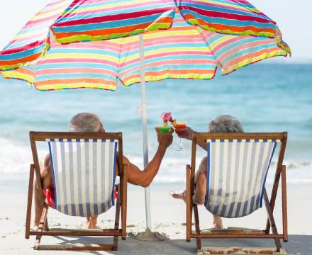 Un couple de personnes âgées boit un cocktail sur la plage