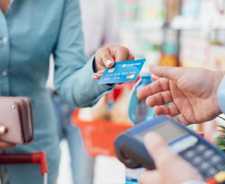 Une femme paie avec sa carte à la caisse d&#039;un supermarché