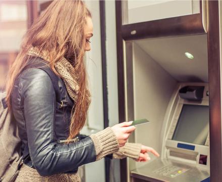 Een jonge vrouw haalt geld af aan de bankautomaat