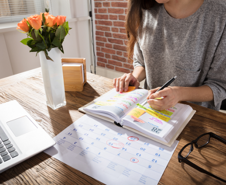 Een vrouw noteert iets in haar agenda